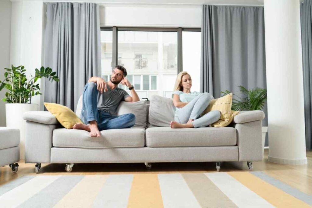 Young couple sitting apart on a sofa, illustrating the emotional uncertainty and lack of commitment often seen in a situationship.
