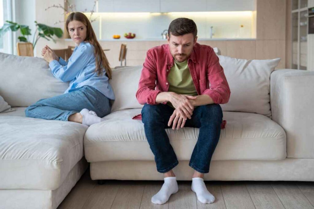 Young couple sitting silently on a sofa, illustrating the emotional distance and uncertainty often experienced in a situationship.